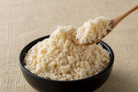 grated parmesan cheese in a wooden spoon on burlap backgroundの写真素材