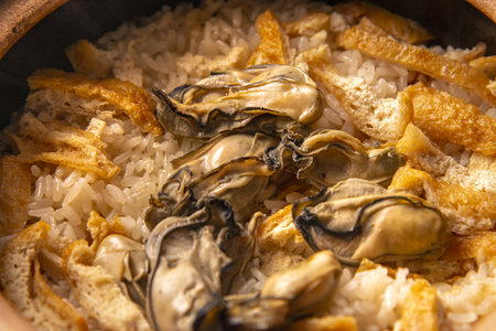 Oysters with rice and fried onion in a pot. Close up.の写真素材