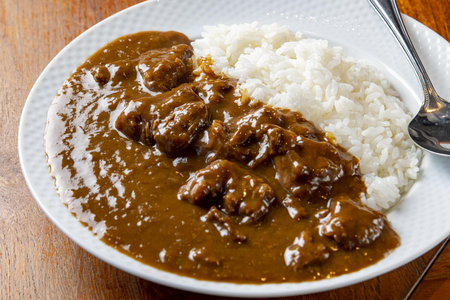 Beef stroganoff with rice in a plate on a wooden tableの写真素材