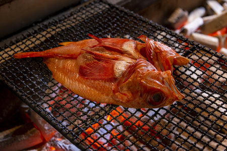 Red tilapia fish roasting on a barbecue grill in a restaurantの写真素材