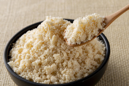 grated parmesan cheese in a wooden spoon in a bowlの写真素材