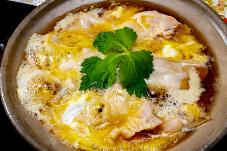 Chicken soup in a clay pot with parsley on a black backgroundの写真素材