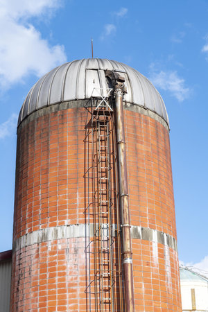 An old silo with a rusty metal frame against a blue skyの写真素材