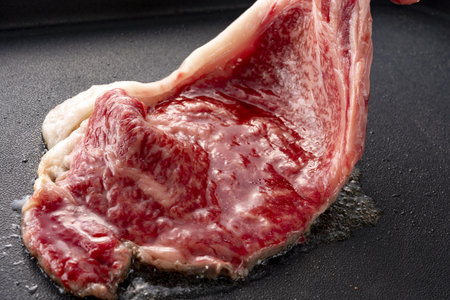 Raw fresh beef steak on black frying pan, closeup view.の写真素材