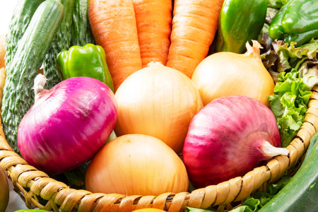 Fresh vegetables in a wicker basket on a white background. Close up. A lot of fresh and delicious vegetables harvested in the fieldの写真素材