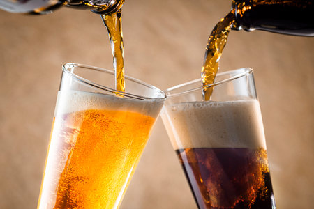 Pouring beer into glasses on wooden background. Close-up.の写真素材