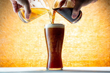 Pouring beer into glass on wooden table with grunge background.の写真素材