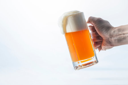 Hand holding a pint of beer isolated on white background with copy space