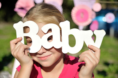 Young girl hold wooden decoration handmade word baby before faseの写真素材