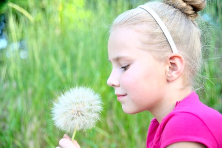 Portrait of a girl with dandelion on natural background.の写真素材