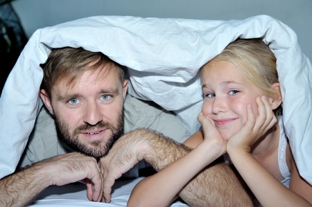 Portrait of a father with his  daughter lying on bedの写真素材