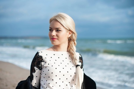 Portrait of the beautiful blonde woman at the  autumn day relaxing on coast feeling goodの写真素材