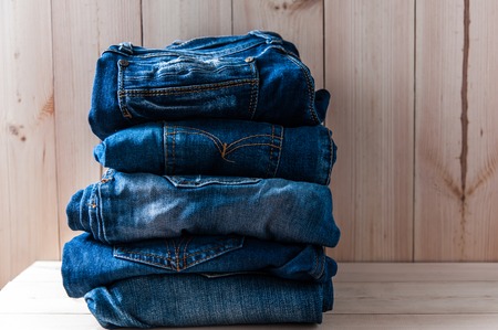 Close up of many blue jeans trouser stack on wooden  background