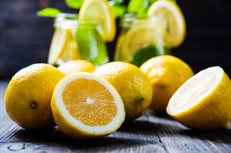 lemons on a dark wooden table, lemonade on background. selective focusの写真素材