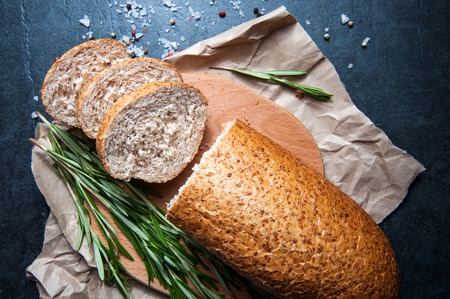 A loaf of bread with rosemary salt and pepper on paper closeupの写真素材