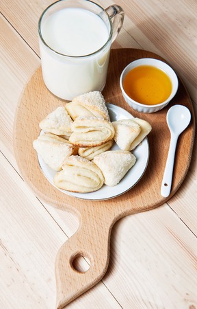 Cheese cookies with honey and milk as a countryside breakfast on wooden cutting boardの写真素材