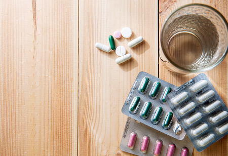 Glass of Water and Pills on wooden background. Copy space, top view