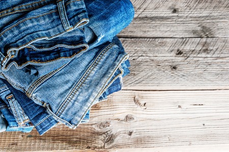 jeans stacked on a wooden background with copy cpaseの写真素材