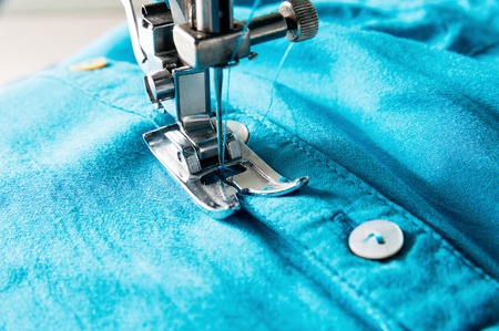 Closeup of sewing machine working part with blue clothの写真素材