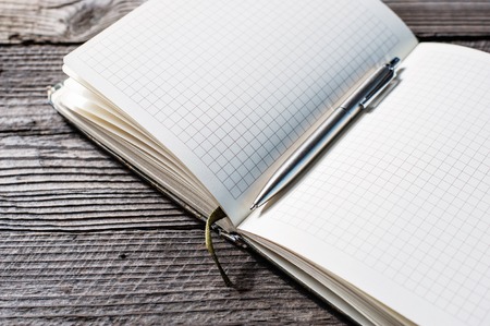 Open notebook blank page with pen on old wooden tableの写真素材