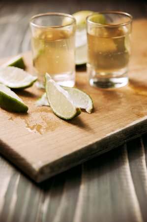 Tequila in Shot Glasses with Lime and Salt on cutting board vintage tonedの写真素材