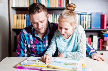 Young father helping her daughter with her school project at home or libraryの写真素材