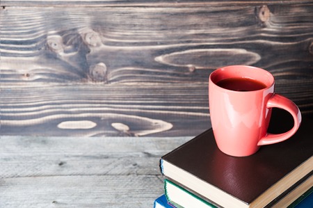 Hot coffee or tea, cocoa, chocolate cup on book with copy space for text against the wooden backgroundの写真素材