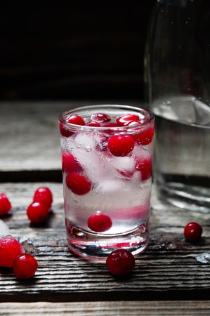 A Bottle and Shot of Vodka with Raspberry on old wooden backgroundの写真素材
