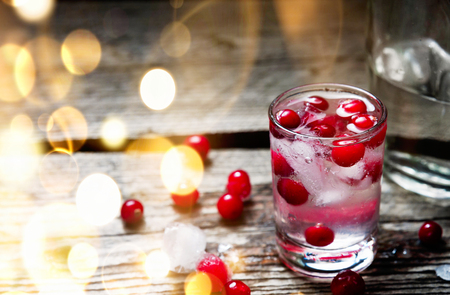 Bottle and Shot of Vodka with Raspberry on old wooden background with bokehの写真素材