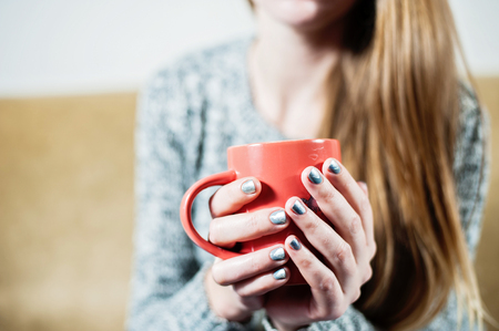 Woman with beautiful manicure holding a pink cup of tea coffeeの写真素材
