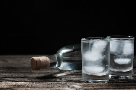 Cold vodka in shot glasses on a black background on wooden tableの写真素材