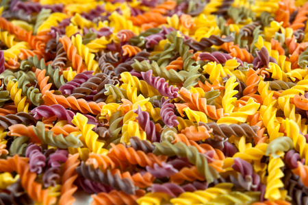 Food background - uncooked three-colored Fusilli durum wheat pasta with spinach and tomatoの写真素材
