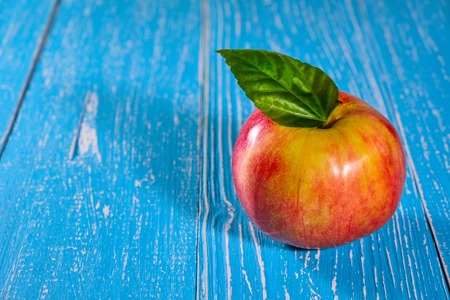 Red apple on blue wooden background closeupの写真素材