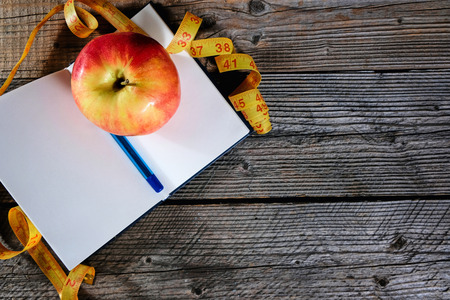 Planning of a diet. A notebook c an inscription - the Diet, a measuring tape, an apple and pen, copyspace.の写真素材