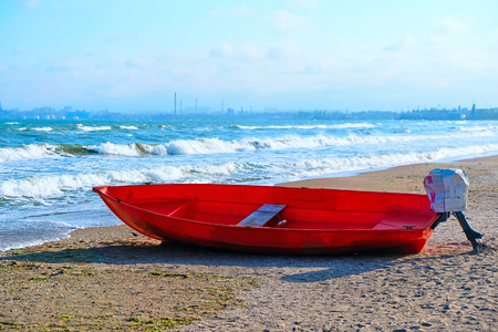 Summer Vacations. The red kayak is parked on the sandy beach on a sunny day, waiting for people to paddle out to sea.の写真素材