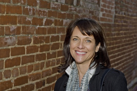 Close up of a smiling woman standing by brick wallの写真素材
