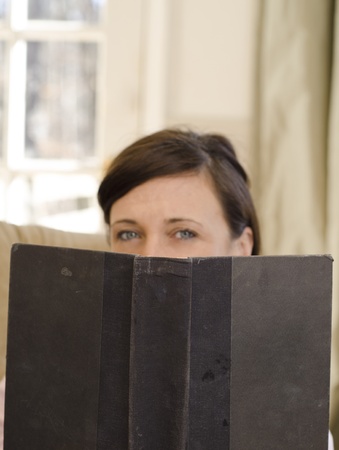 Blurred woman reading a focused and mysterious bookの写真素材