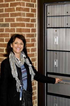 Pretty business woman checking the office mail boxの写真素材