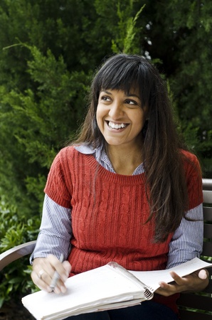 Pretty Middle-Eastern student looking up and smiling at a friendの写真素材