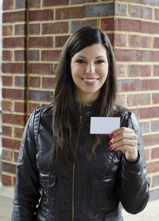 Beautiful woman in black leather offering her cardの写真素材