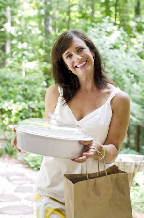 Pretty woman bringing a covered dish to a neighborの写真素材