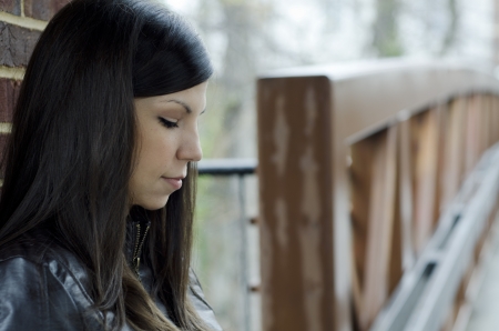 pretty woman leaning against a wall and thinkingの写真素材