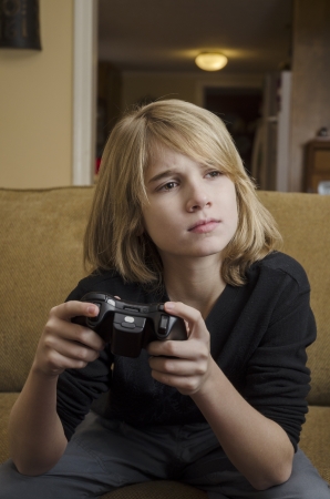 Young teen concentrating on playing a video gameの写真素材