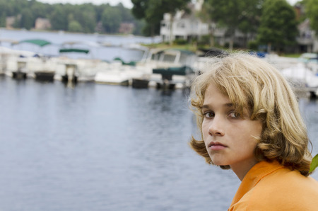 bored and priviledged boy siting by the docsの写真素材