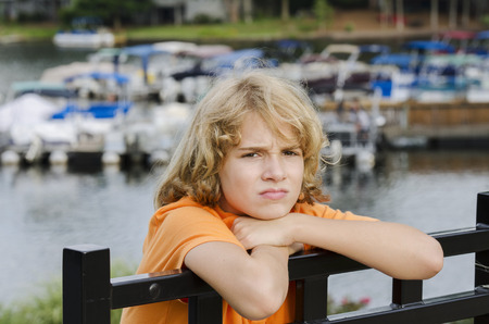 bored young teen is sitting at the docks with nothing to doの写真素材