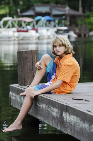 Young boy sitting on a dock in the bayの写真素材