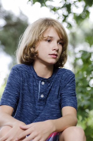 Young boy sitting and relaxing outside on a nice dayの写真素材