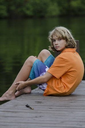 Young kid sitting back relaxing on the dockの写真素材