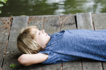 Bored teen laying back and relaxing on the dockの写真素材