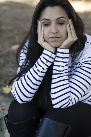 Attractive young Indian woman sitting and lost in her thoughtsの写真素材